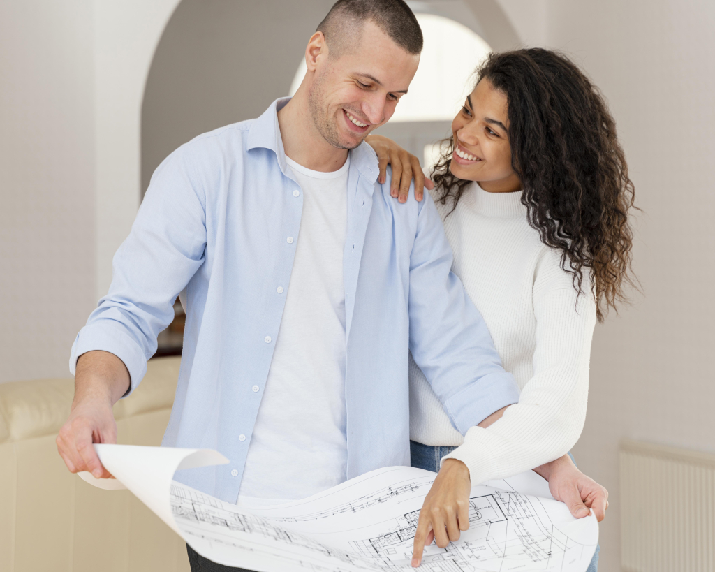 pareja sonriente viendo planes de la propiedad en venta.