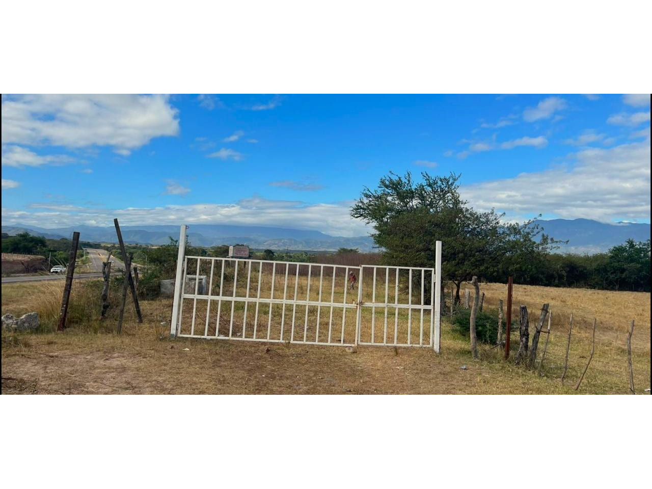 Entrada de acceso con portón de color blanco del terreno para agricultura ubicado en el CA-5, Comayagua, Honduras.