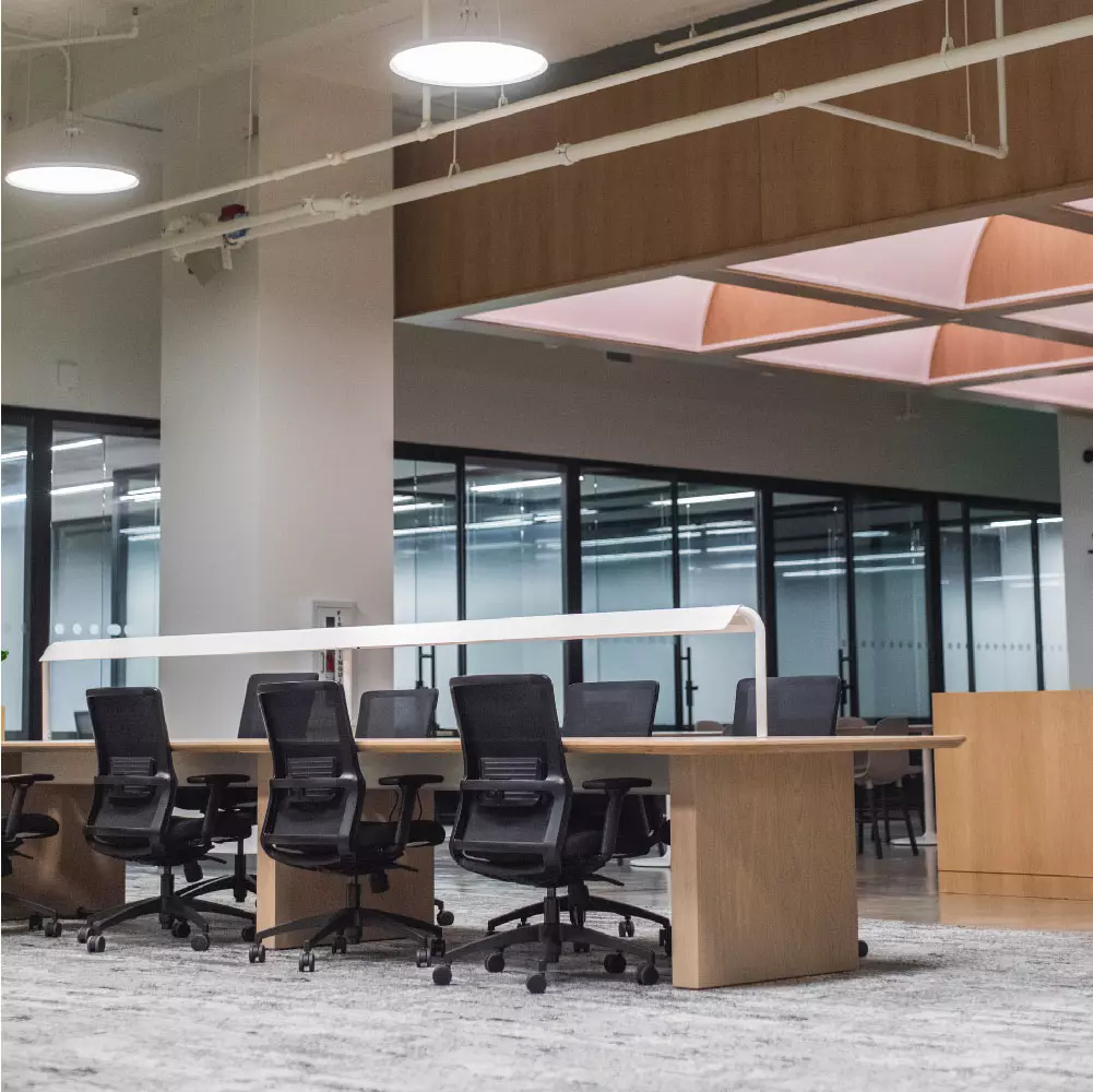 Oficina interna amueblada en el edificio de vertis color blanco con muebles de madera techo de tabla yeso con lamparas colgantes led.