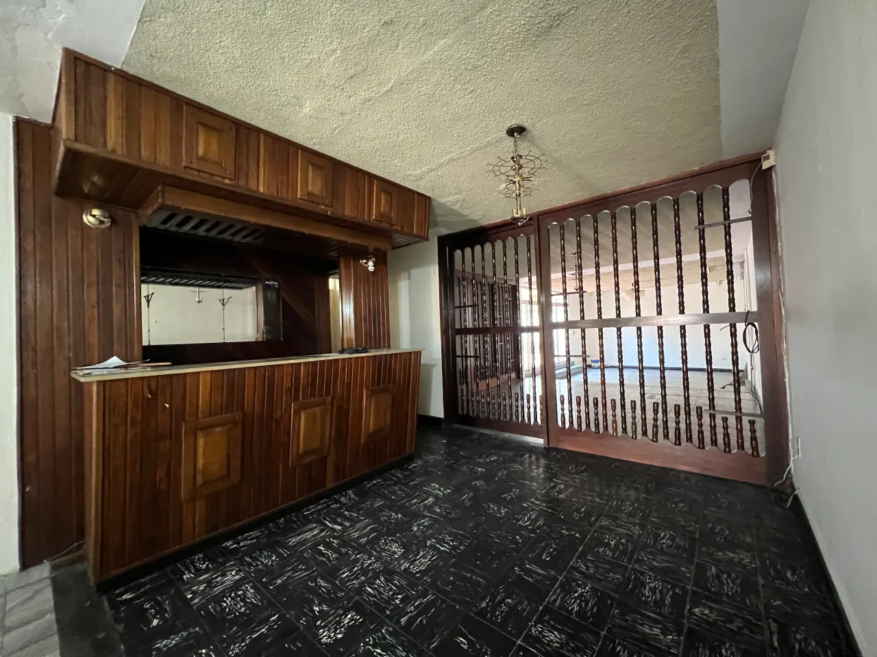 Habitación con un área de bar de madera color cafe oscuro, con acceso a la sala principal.