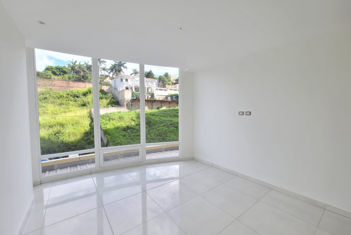 Habitación con paredes de color blanco, con suelo de porcelanat, cuenta con closet de madera clara, cuenta con un amplio ventanal y su propio aire acondicionado más su baño privado.