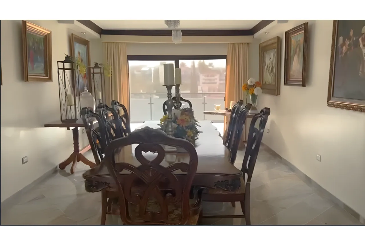 Comedor de la casa en venta, amplio con 8 sillas piso de cerámica de madera, techo color blanco con lámpara colgante y enfrente una puerta corrediza con vista al patio trasero.