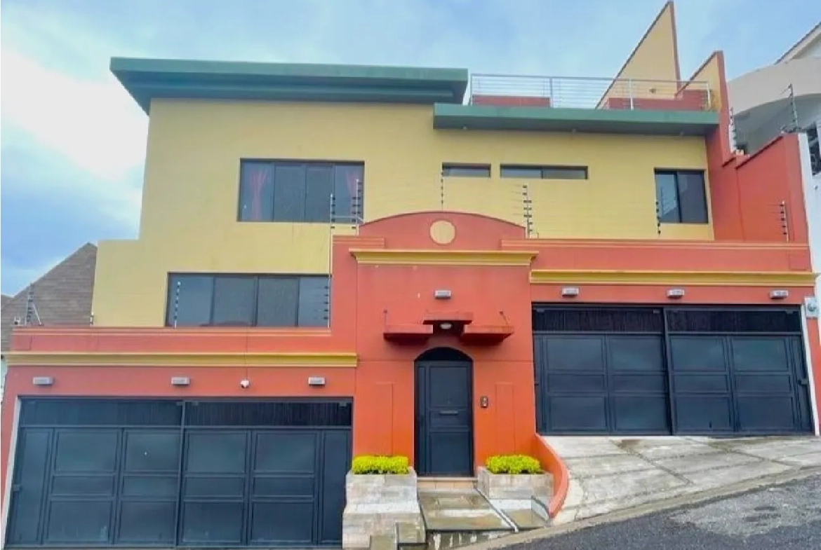 Venta de casa cuenta con fachada de color amrarillo y naranja, cuenta con 4 portones techados.