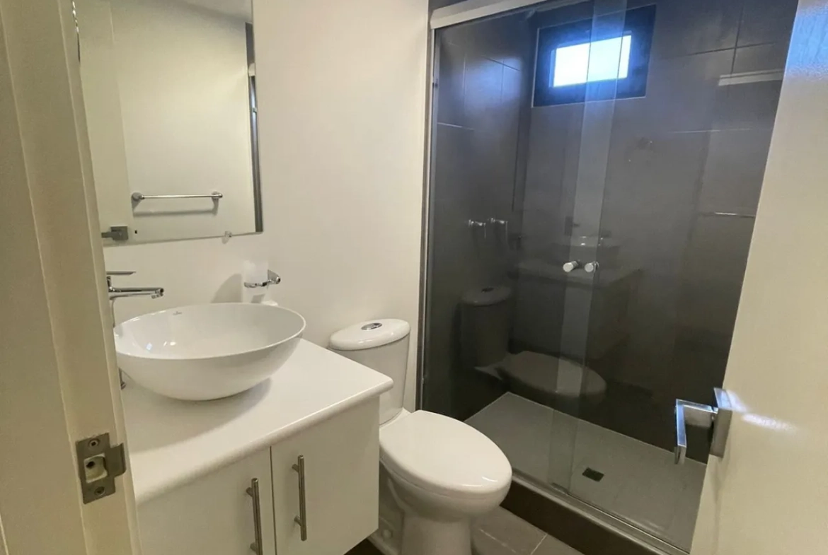 baño con mueble de lavamanos, espejo y puerta de vidrio en ducha
