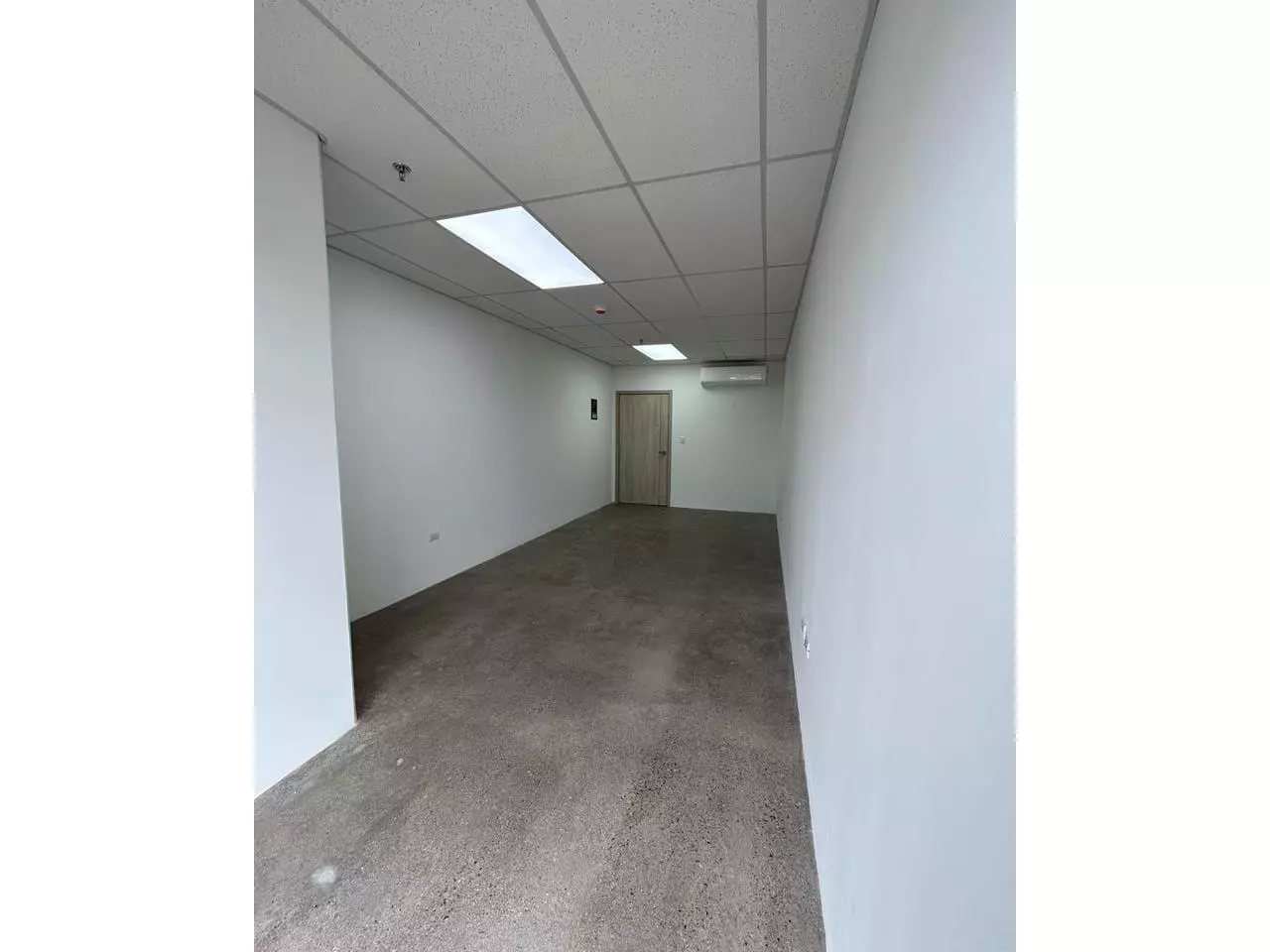 Oficina en alquiler con paredes color blanco y piso de cemento pulido.