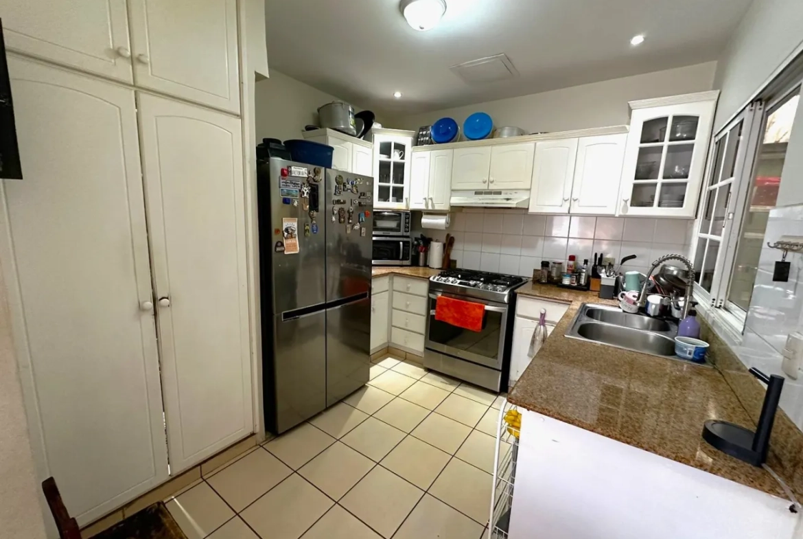La cocina cuenta con muebles de color blanco y espacio para colocar los electrodomesticos.
