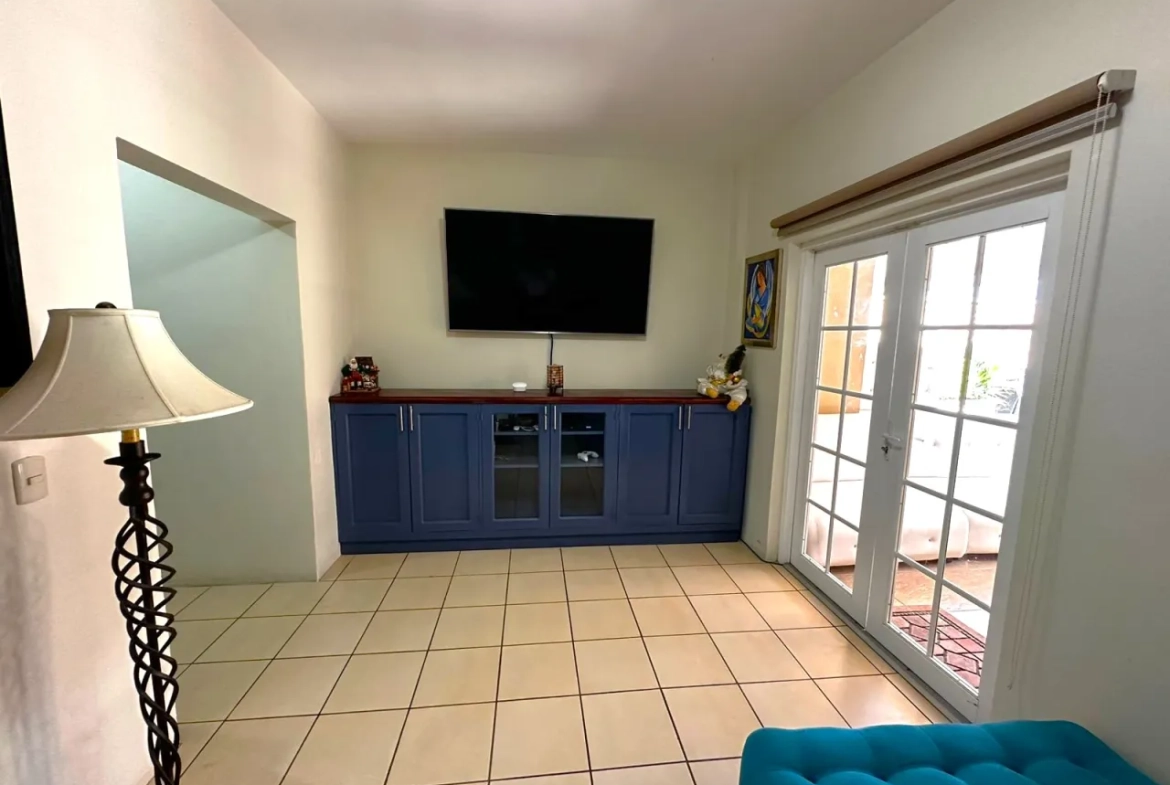 Sala de televisión cuenta con un televisor plasma con muebles de color azul, una puerta de color blanca que brinda acceso al área social del exterior de la casa.