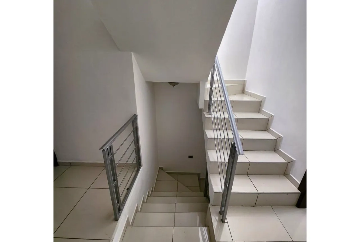 Escaleras que dan aceso al segundo nivel de la casa, cuenan con paredes de color blanco, suelo de porcelanato y los barandales son metalicos de color gris.