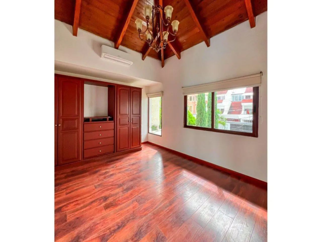Habitación con closet de madera, un aire acondicionado, techo de madera con un abanico aéreo.