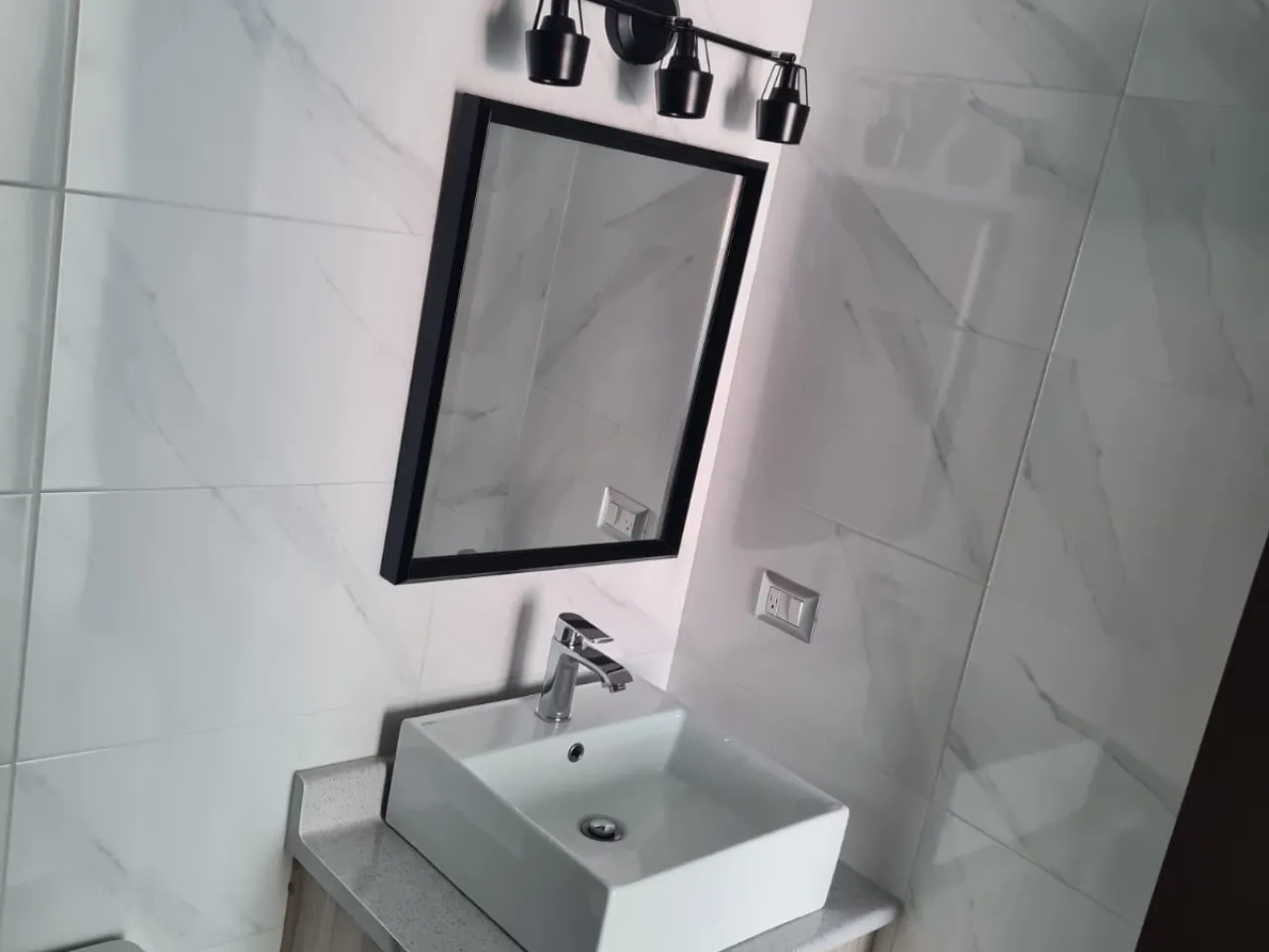 baño enchapado con espejo y mueble de lavamanos aéreo
