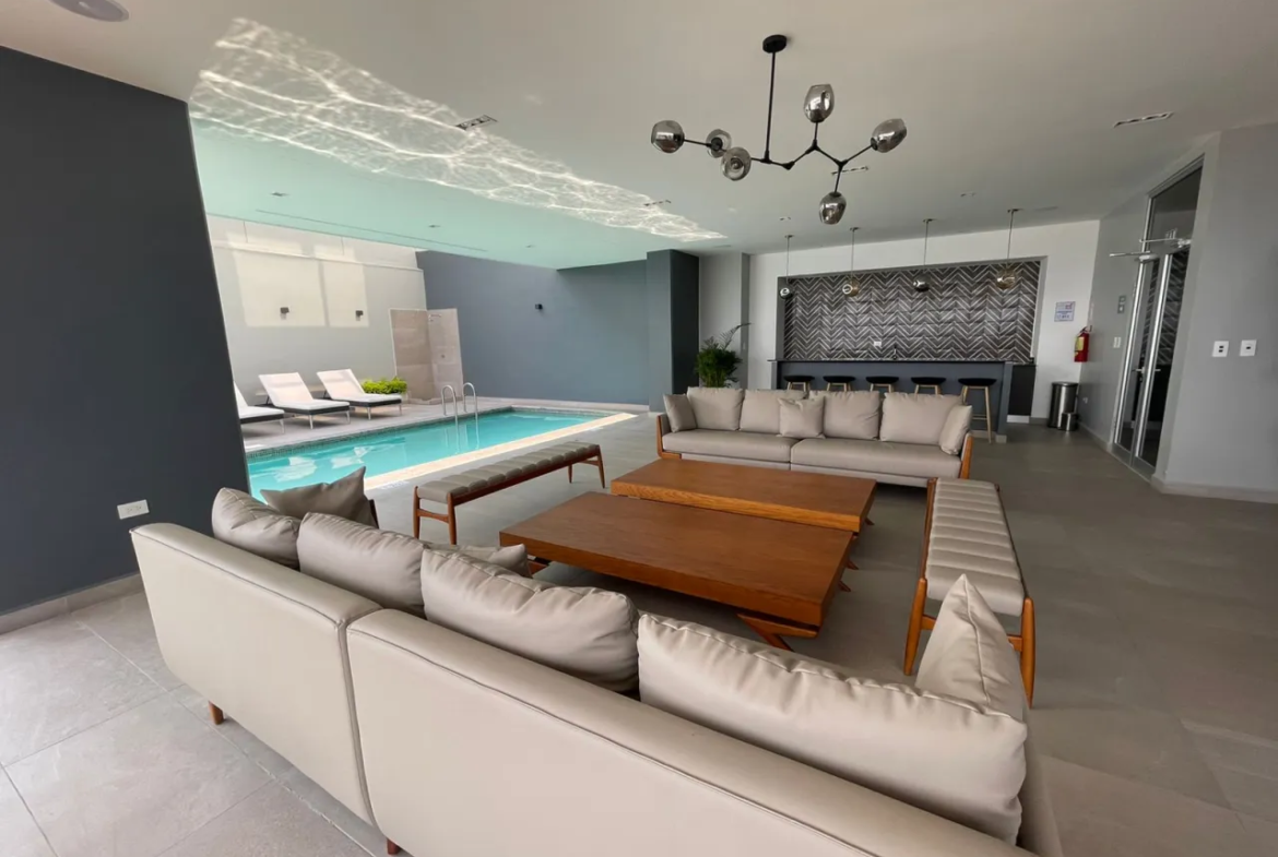 Área social con piscina, mesas amplias y zofas de color crema