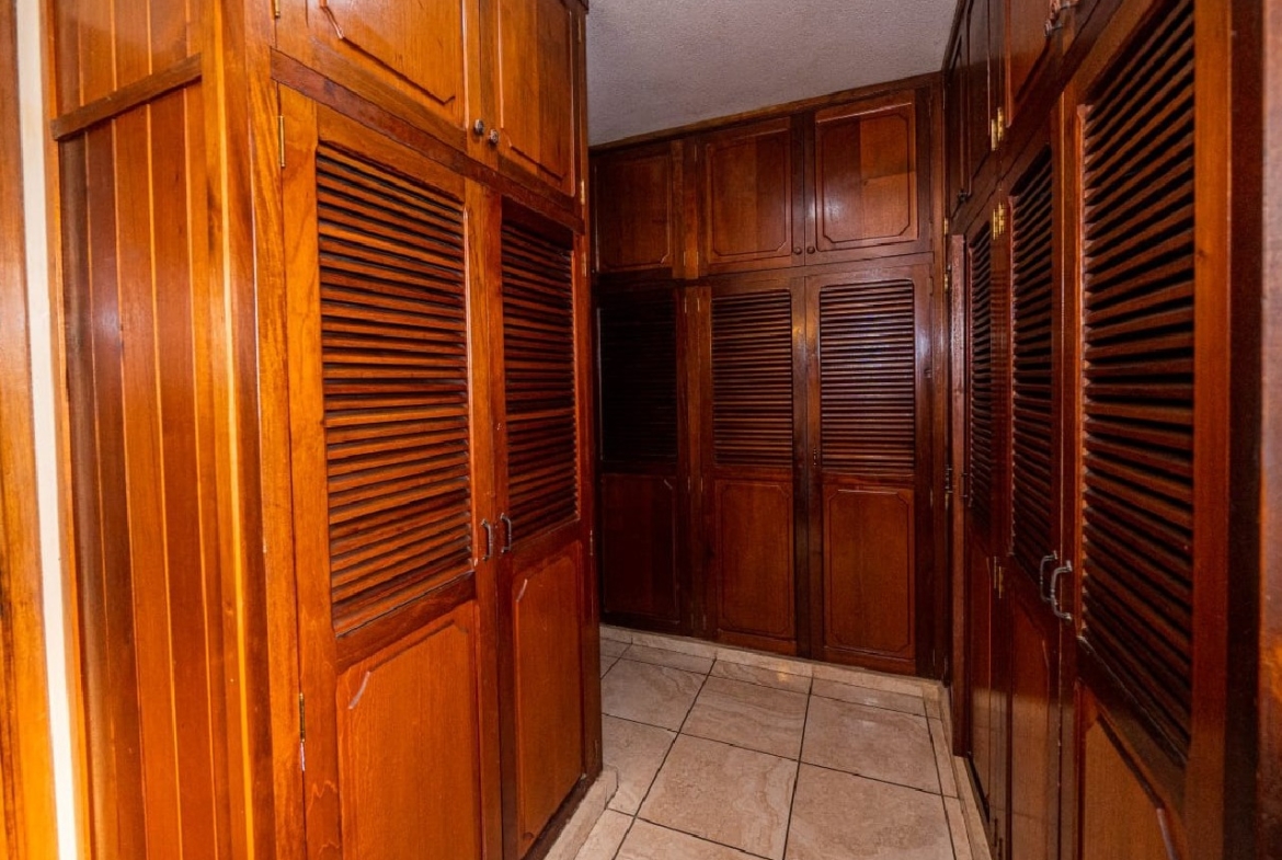 Un walk-in closet amplio de madera color café con varios espacios para acomodar tus pertenecias