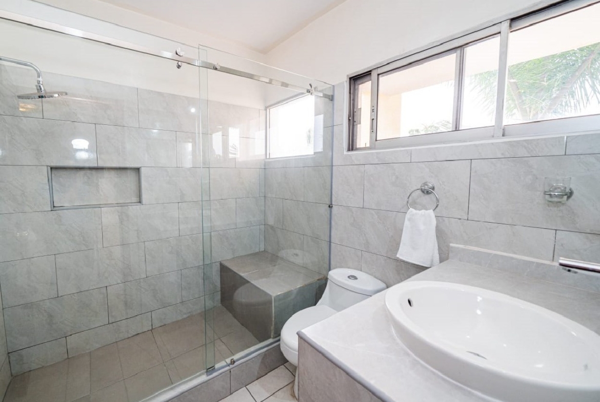 Baño elegante que tiene espacio para ducha con puertas corredizas de cristal, con pared de cerámica blanca