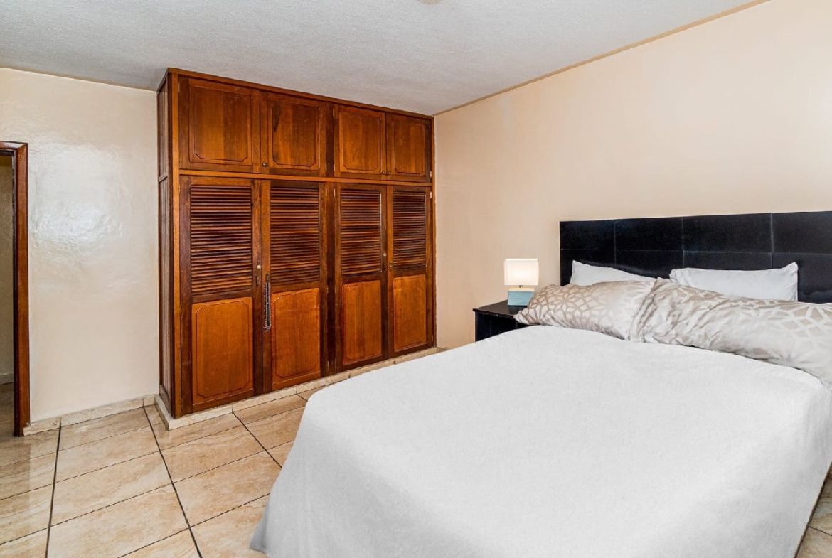 Habitación secundaria tiene una cama matrimonial con su respectiva cabezera color azul y también un closet de color de madera