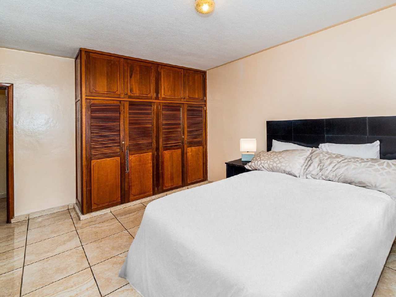Habitación secundaria tiene una cama matrimonial con su respectiva cabezera color azul y también un closet de color de madera