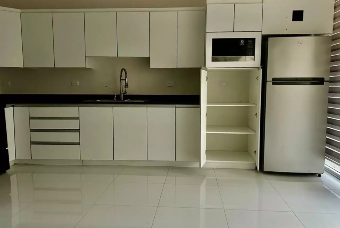 Área de cocina con linea blanca y muebles madera en apartamento ubicado colonia lara.