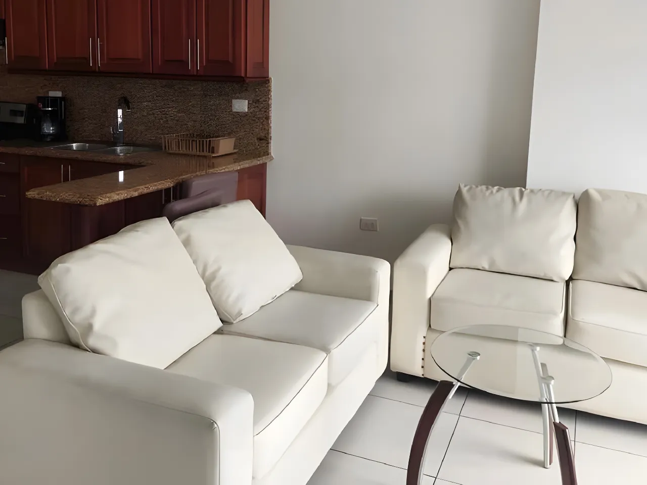 La sala de este apartamento cuenta con sofás blancos , mesa de centro de cristal el cual puedes adornar y también un televisor para hacer más completo este espacio.