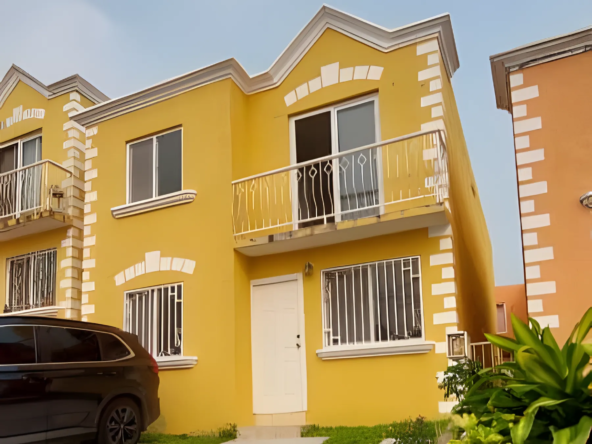 La fachada de esta casa en venta es de color amarillo, cuenta con espacio para dos estacionamientos y un balcón.